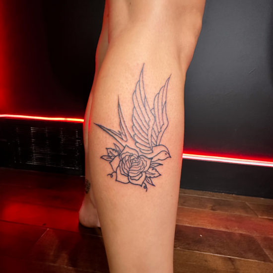 Picture of a traditional swallow and rose leg tattoo.