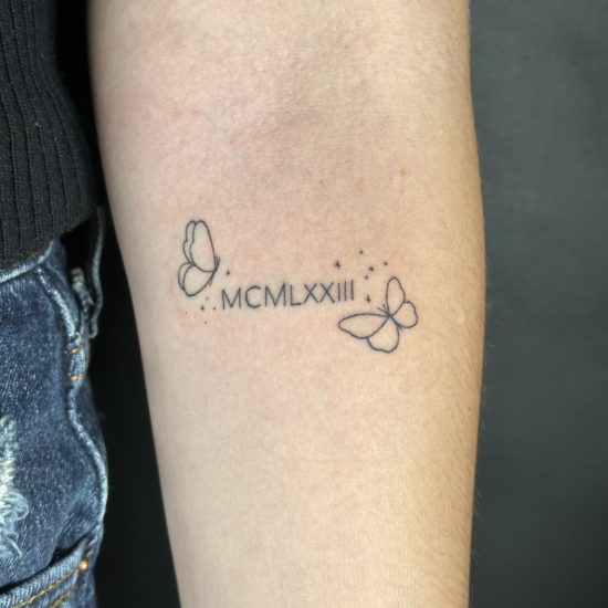 Picture of script and butterfly linework tattoo.