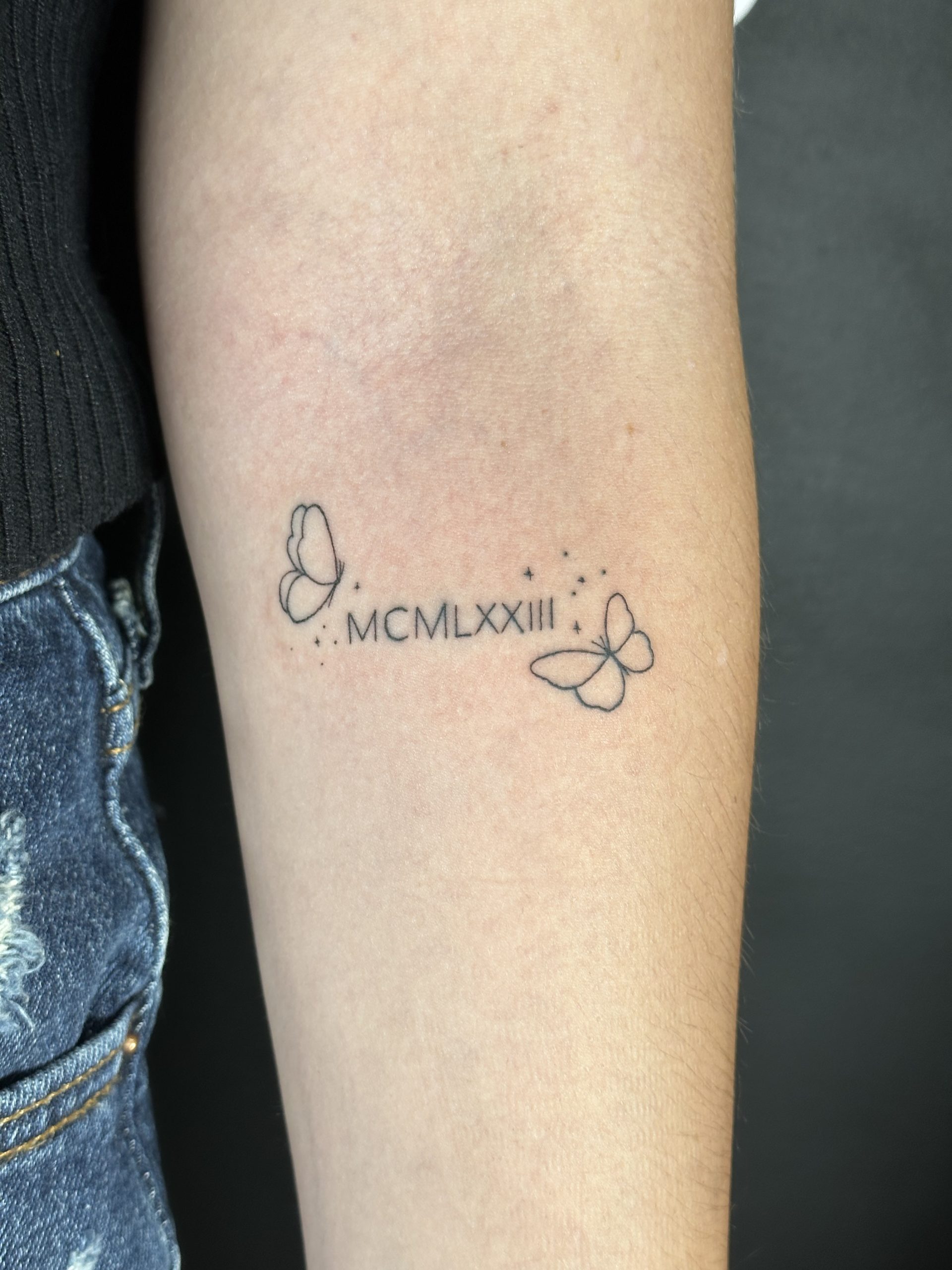 Picture of script and butterfly linework tattoo.